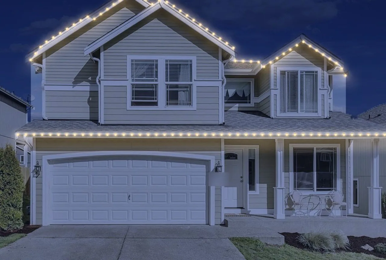 The same sample house in the evening with warm white Christmas lights on the roofline